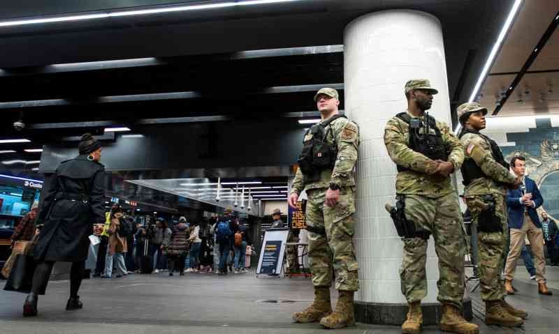 La Guardia Nacional del Estado de Nueva York vigila a los viajeros en un puesto de control dentro de la entrada de la estación de metro